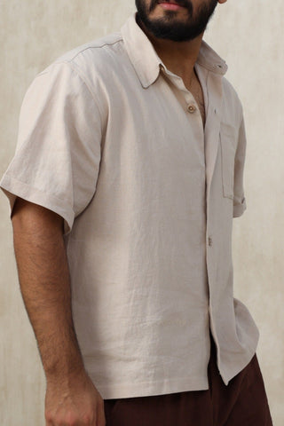 Man wearing a light-colored Everseason shirt and dark shorts standing against a neutral wall.
