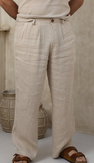 Man wearing a beige Everseason 100% linen pants standing in a marble room.