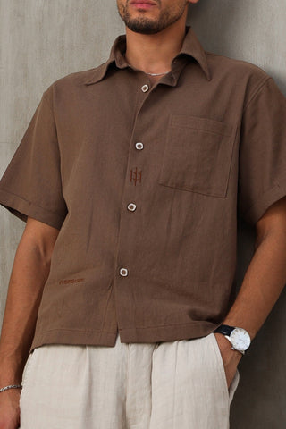 Man wearing aA Everseason brown shirt and sunglasses against a gray wall