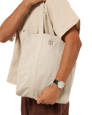 Person holding a beige EVERSEASON linen tote bag with a logo on a white background